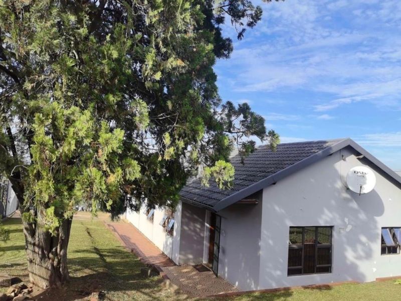 A view of the front exterior of the house featuring a tiled roof, paved walkway, and established garden area.
