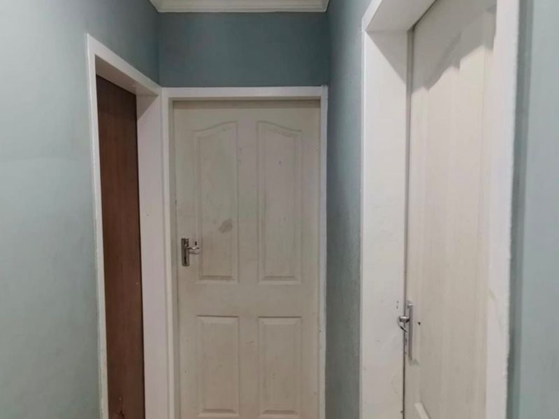A narrow interior hallway featuring multiple internal doors and painted walls showing signs of wear.
