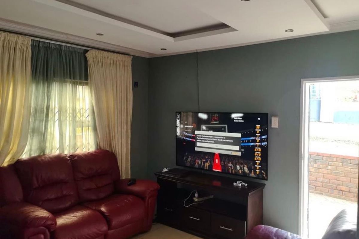 A comfortable living room featuring a recessed ceiling with downlights, tiled flooring, and a sliding door providing access to the exterior.