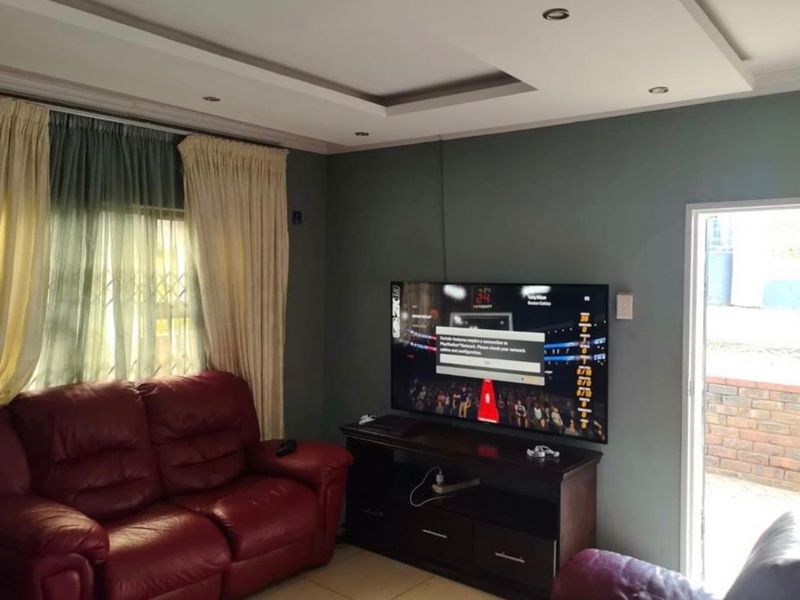 A comfortable living room featuring a recessed ceiling with downlights, tiled flooring, and a sliding door providing access to the exterior.