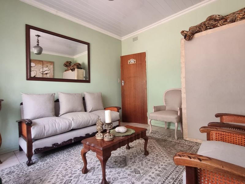 A cozy living room featuring a tongue and groove ceiling, tiled flooring, and a classic timber door.