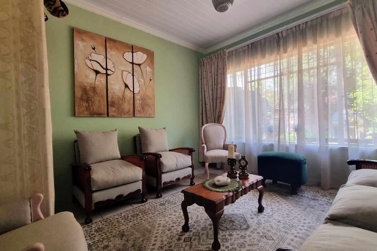 A cozy living room featuring a tongue and groove ceiling, tiled flooring, and a large window with security bars allowing natural light.