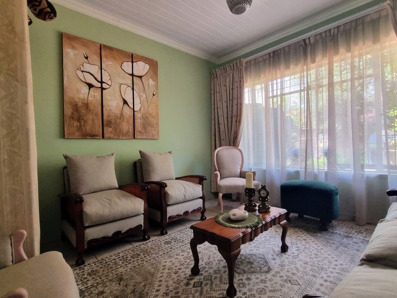 A cozy living room featuring a tongue and groove ceiling, tiled flooring, and a large window with security bars allowing natural light.