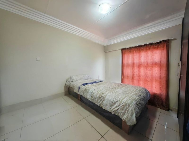 A bedroom featuring tiled flooring, ceiling cornice detailing, and a built-in wardrobe, providing a functional and neutral living space.