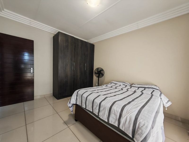 A functional bedroom featuring tiled flooring, a built-in wardrobe, and decorative ceiling cornicing.