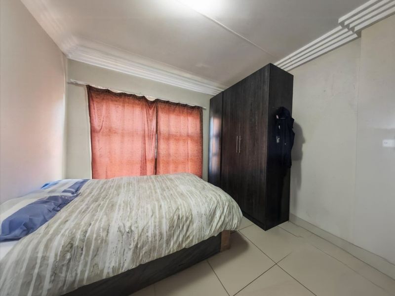 A bedroom featuring tiled flooring, cornice detailing, and a built-in dark wood wardrobe.