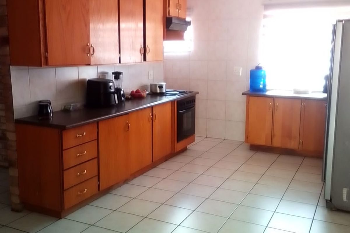 A functional kitchen featuring wooden cabinetry, tiled flooring, and built-in appliances, offering a classic layout with ample storage space.