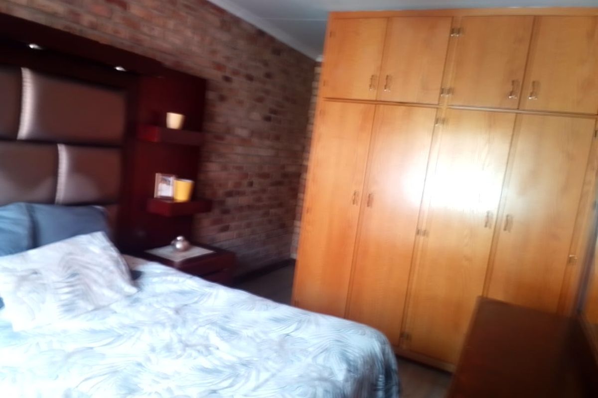A bedroom featuring an exposed brick feature wall and extensive built-in wooden cabinetry for storage.