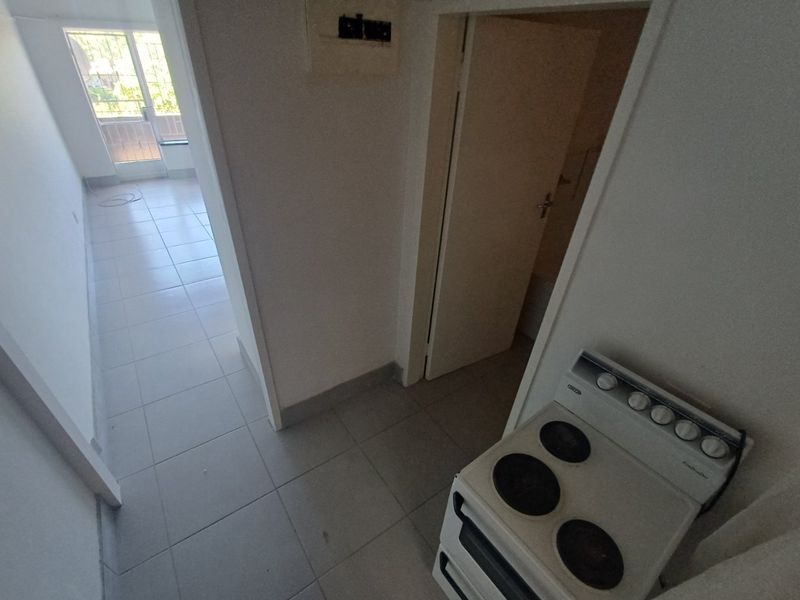 A view of a kitchen area featuring a freestanding stove, tiled flooring, and access to an adjacent room with a balcony.