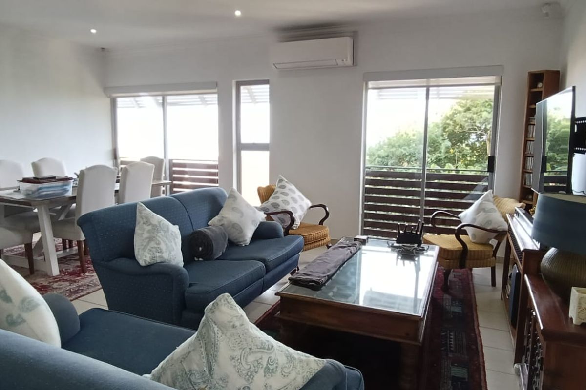 Spacious open-plan living and dining area featuring tiled flooring, recessed lighting, a wall-mounted air conditioner, and sliding glass doors leading to an outdoor space.