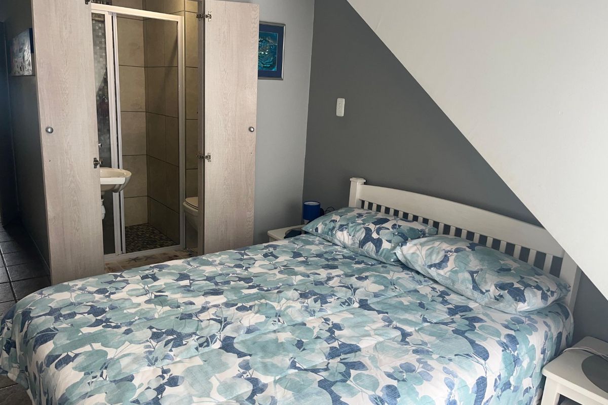 A bedroom featuring a sloped ceiling and an integrated en-suite bathroom with a shower enclosure and tiled finishes.