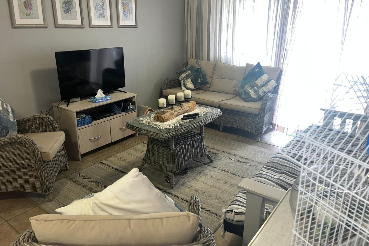 A comfortable living room featuring tiled flooring and a large sliding glass door that provides ample natural light.