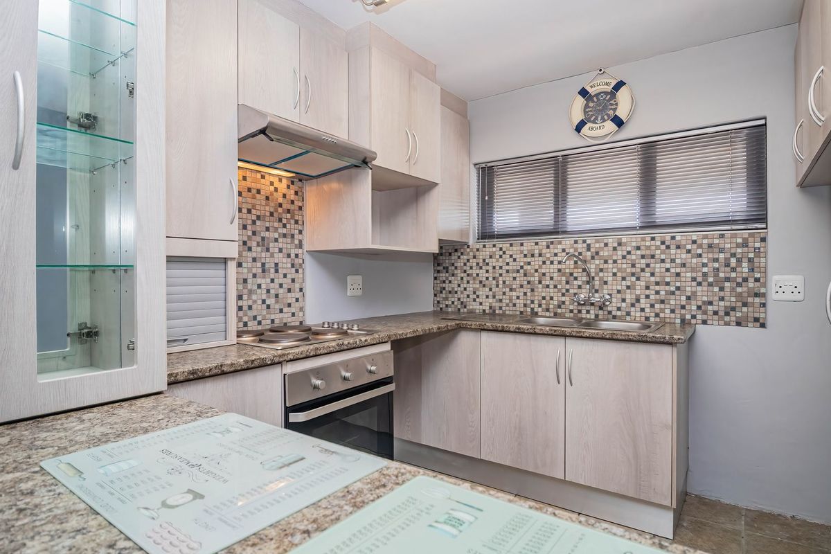 A well-maintained kitchen featuring light wood-grain cabinetry, granite countertops, a mosaic tile backsplash, and integrated stainless steel appliances.