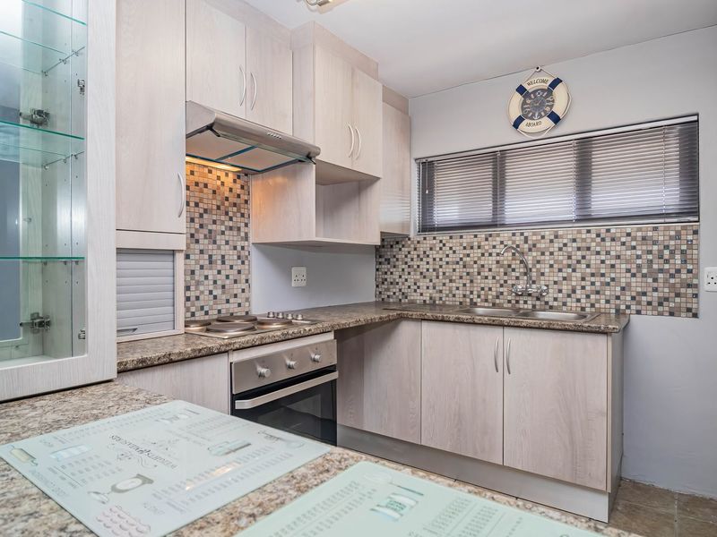 A well-maintained kitchen featuring light wood-grain cabinetry, granite countertops, a mosaic tile backsplash, and integrated stainless steel appliances.