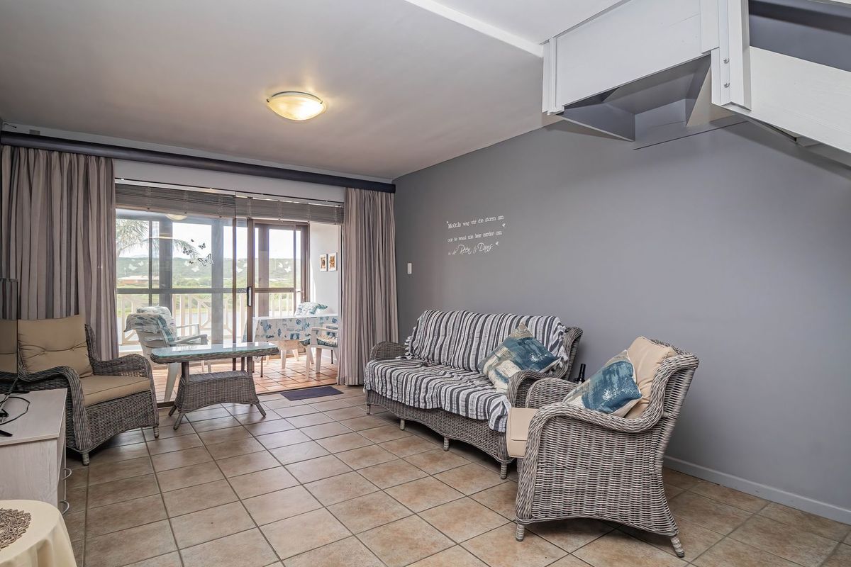 A living room featuring tiled flooring, a staircase, and large sliding glass doors that provide access to an outdoor patio area.