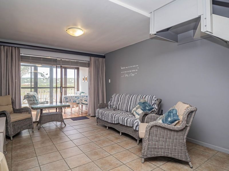 A living room featuring tiled flooring, a staircase, and large sliding glass doors that provide access to an outdoor patio area.