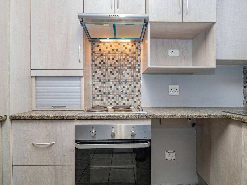 A well-maintained kitchen featuring light wood-grain cabinetry, granite countertops, a mosaic tile backsplash, and integrated stainless steel appliances.