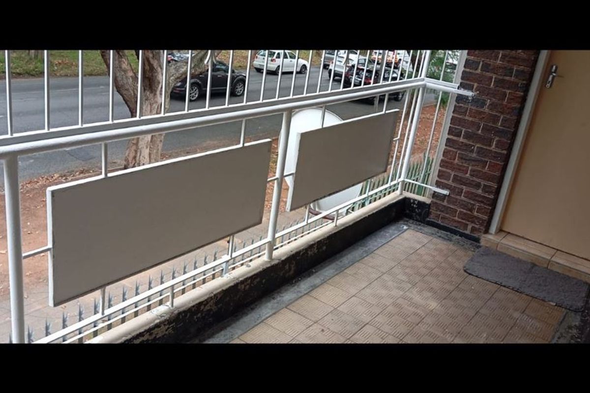 A small balcony featuring a metal balustrade, tiled flooring, and direct access to the apartment interior via an exterior door.