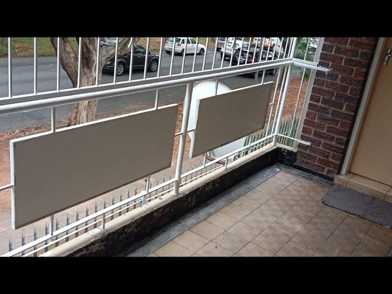 A small balcony featuring a metal balustrade, tiled flooring, and direct access to the apartment interior via an exterior door.