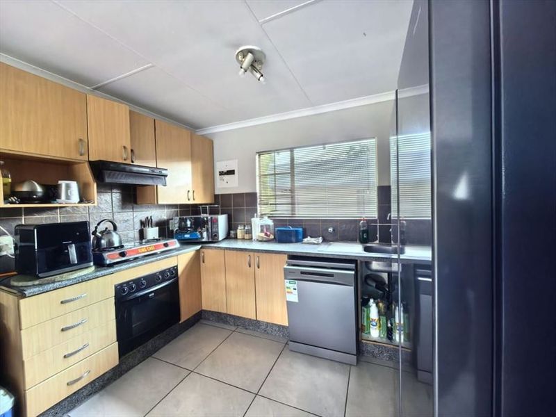 A functional kitchen featuring laminate cabinetry, built-in oven, extractor fan, tiled backsplash, and tiled flooring, offering a practical layout for daily use.