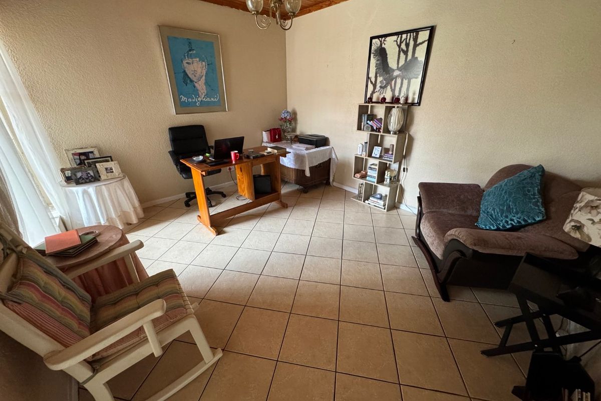 A living area featuring tiled flooring and a timber plank ceiling, currently utilized as a home office space.