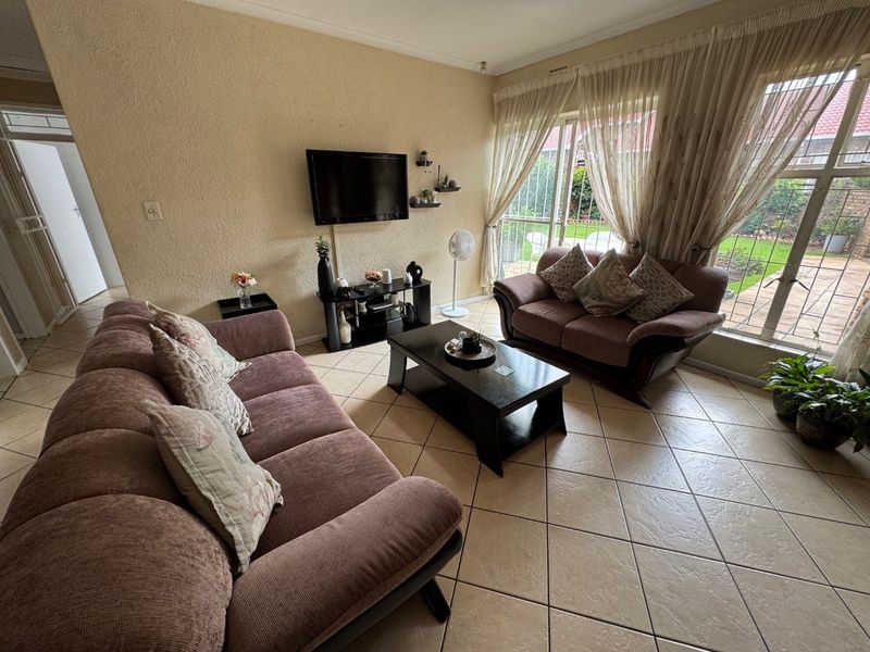 A living room featuring tiled flooring and a large sliding glass door providing access to the garden area.