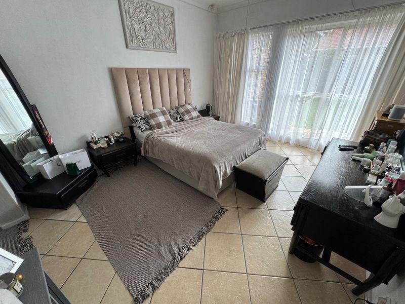 A spacious bedroom featuring tiled flooring and large sliding glass doors that provide natural light and access to the outdoor area.