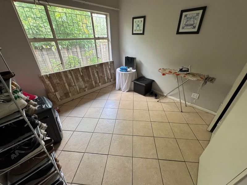 A functional laundry or utility room featuring tiled flooring and a large window, providing ample natural light and space for household tasks.