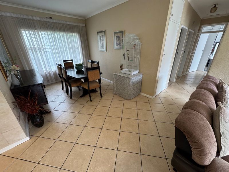 Open plan living and dining area featuring neutral ceramic floor tiles and access to the hallway.