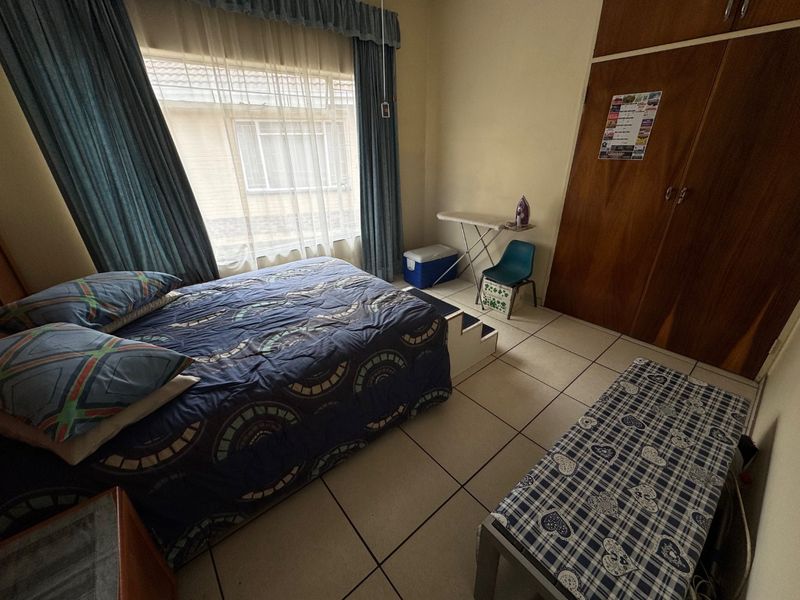 A functional bedroom featuring tiled flooring and a built-in wooden wardrobe, offering a neutral base for potential interior updates.
