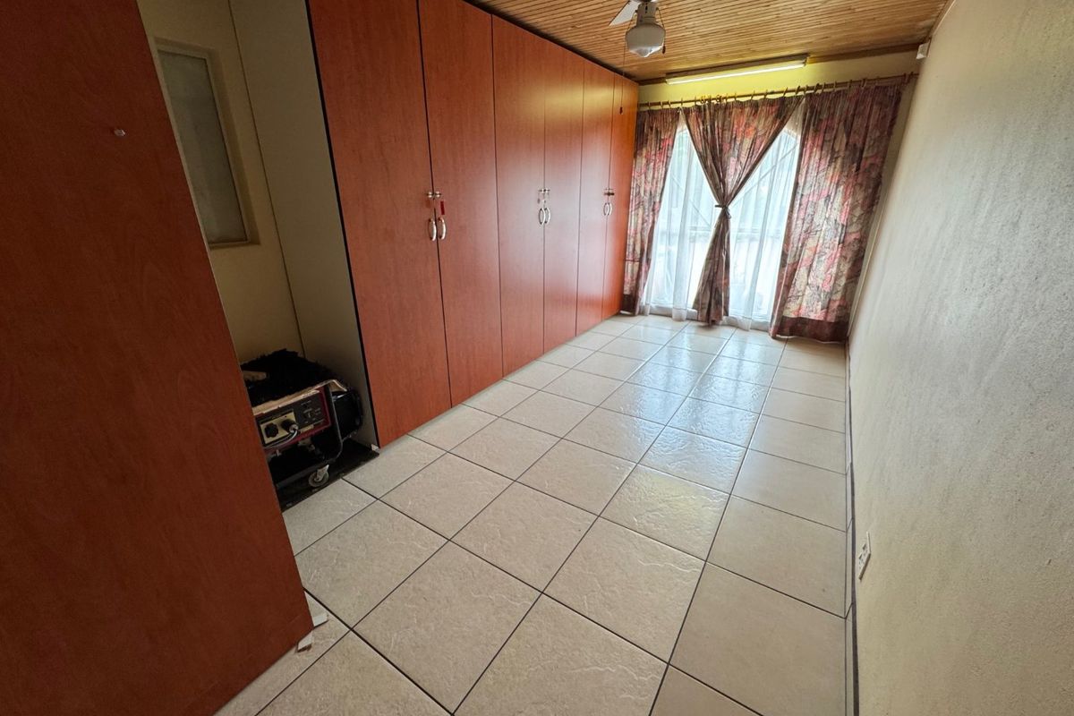 A bedroom featuring built-in cupboards, tiled flooring, and a timber ceiling with a central fan.