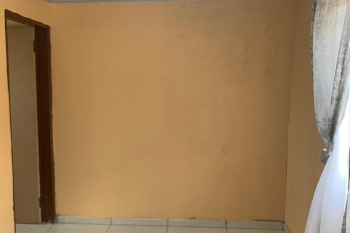 An empty bedroom featuring tiled flooring, ceiling cornicing, and a simple flush mount light fixture, ready for personalization.