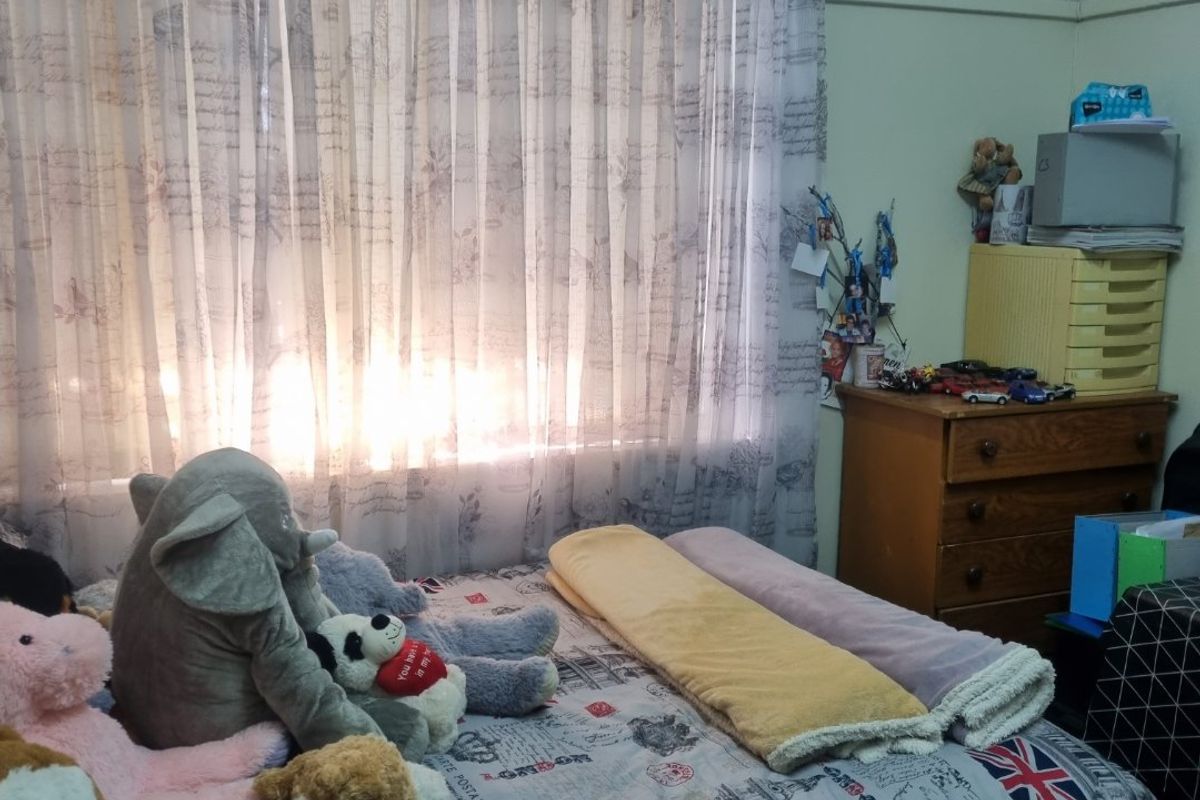 A bedroom featuring a window with sheer curtains and standard wall finishes.