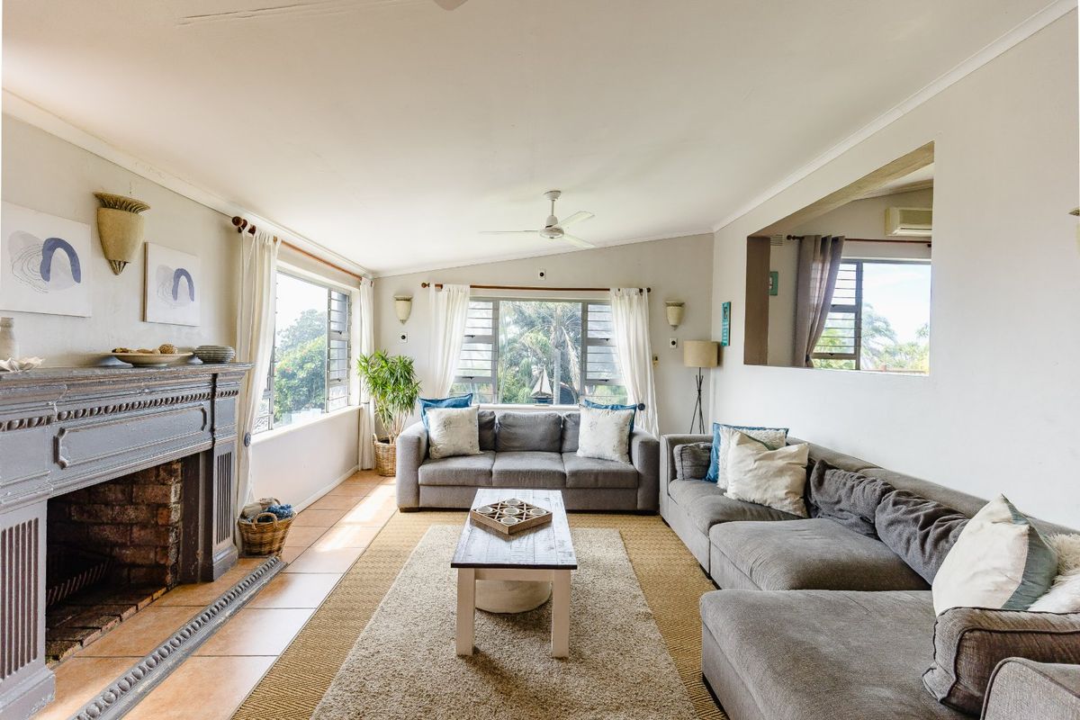 Spacious living room featuring a classic fireplace, tiled flooring, and large windows that provide ample natural light and garden views.
