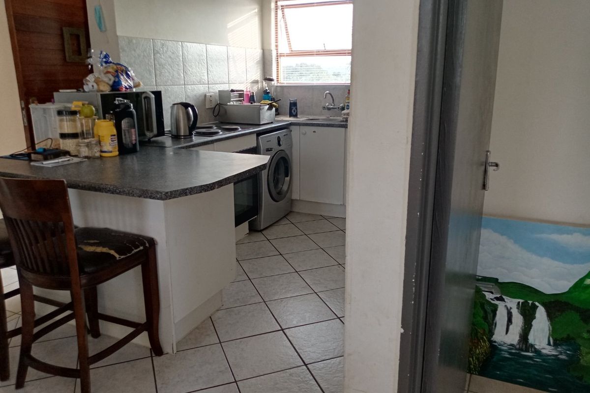 A functional kitchen featuring tiled flooring, laminate countertops, a built-in oven, and a tiled backsplash, offering a practical layout for daily use.