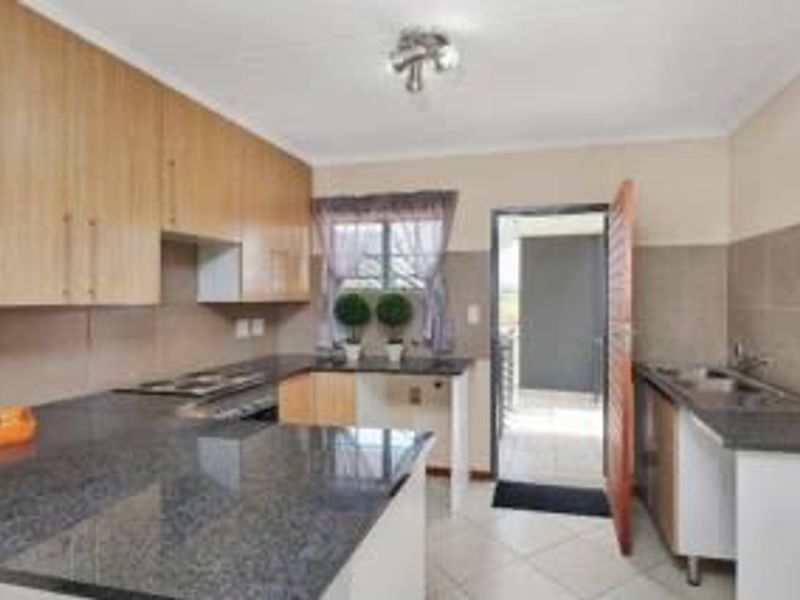 Functional kitchen featuring granite countertops, ample built-in cabinetry, tiled backsplash, and direct access to an outdoor balcony area.