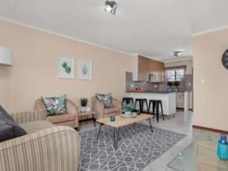 Open-plan living area featuring a functional kitchen with a breakfast bar island and tiled flooring throughout.