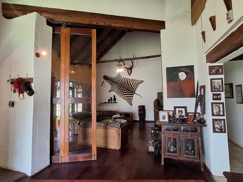 Spacious living area featuring exposed timber beams, a high thatched ceiling, and warm wooden flooring, creating a rustic and character-filled atmosphere.