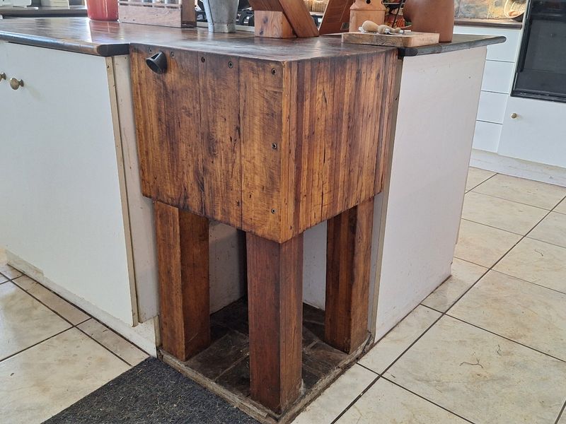 A kitchen island featuring a wooden butcher block end section, white cabinetry, and ceramic tiled flooring.