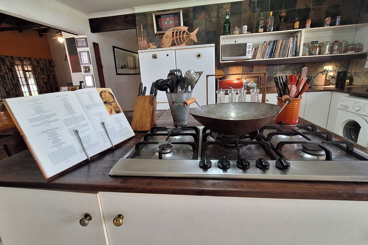 A functional kitchen featuring a central island with a gas cooktop, slate tile backsplash, and built-in cabinetry with a wooden countertop.