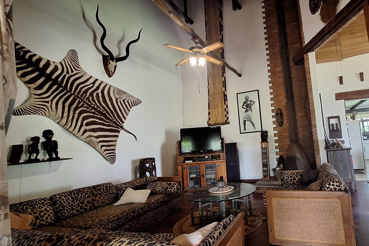 Spacious living room featuring a vaulted ceiling with exposed timber beams, a brick fireplace, and hardwood flooring.