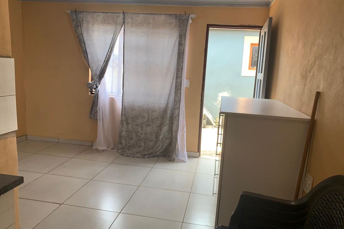 A living area featuring tiled flooring and direct access to an outdoor space, requiring cosmetic updates to the wall finishes.