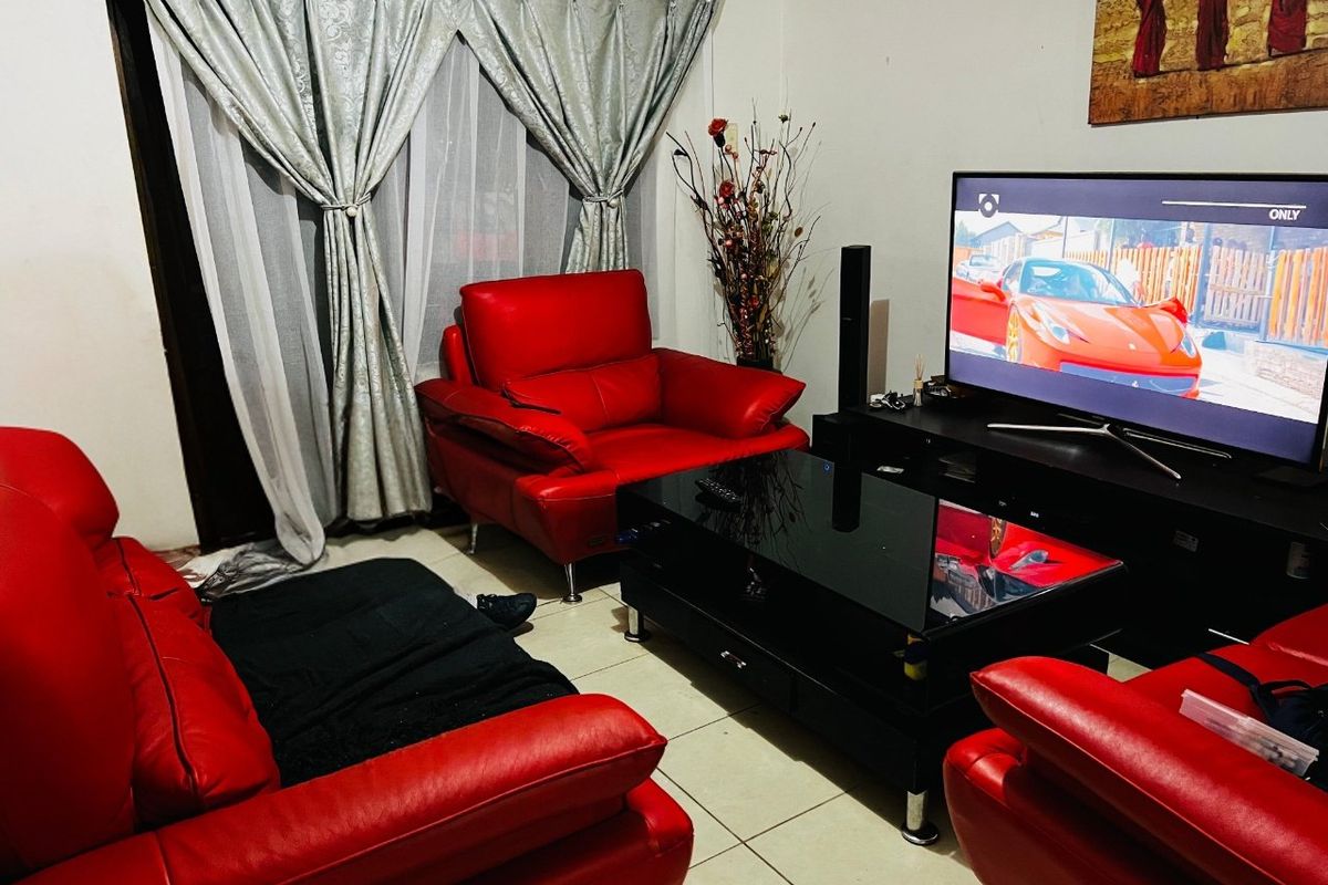 A living room featuring tiled flooring and a sliding glass door with curtains, providing access to an outdoor area.