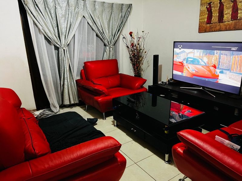 A living room featuring tiled flooring and a sliding glass door with curtains, providing access to an outdoor area.