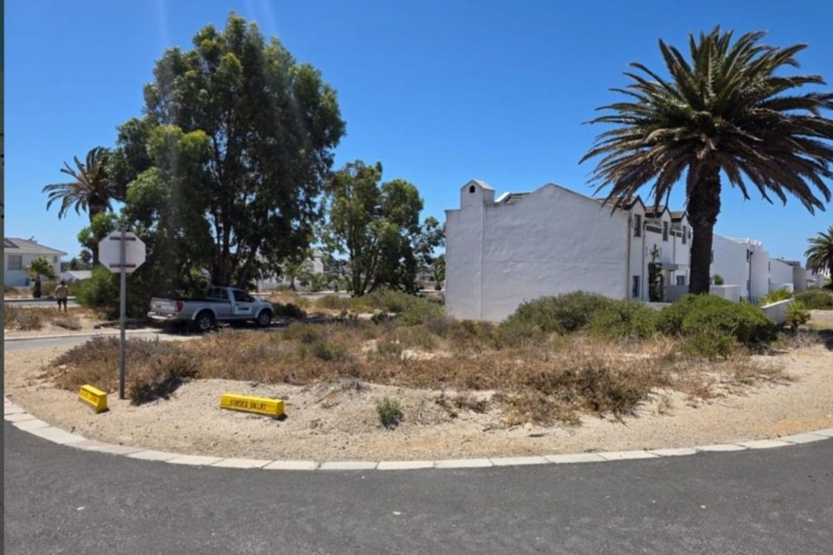 A street-level view of the property approach, showing the paved road, verge, and surrounding residential landscape.