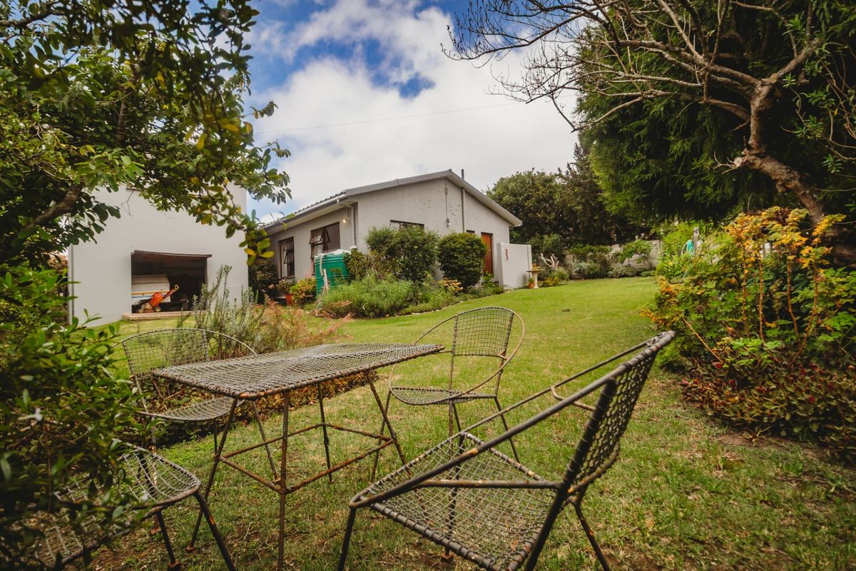 A view of the rear garden and lawn area, featuring established landscaping, a water tank, and access to the garage.