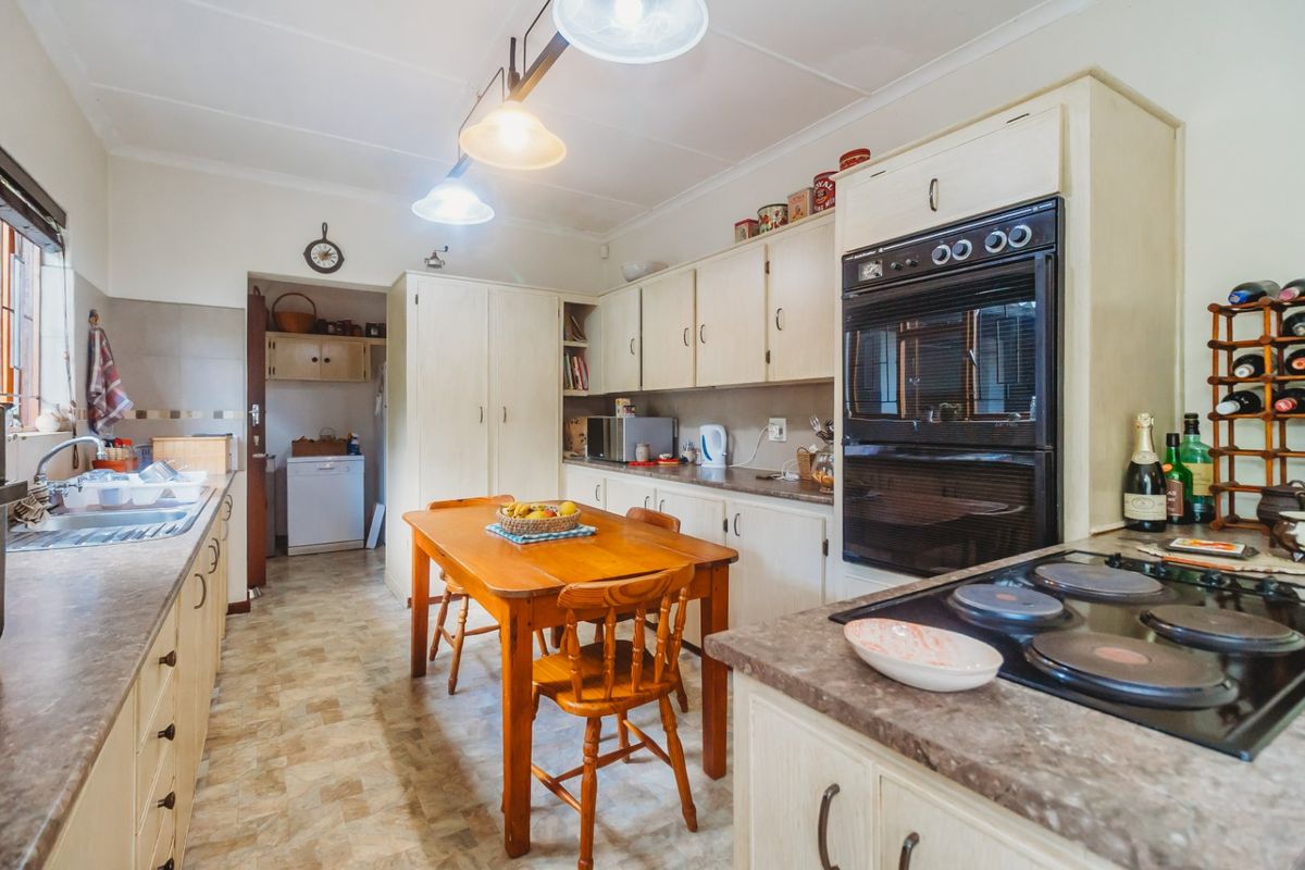 A functional kitchen featuring built-in cabinetry, a double wall oven, electric cooktop, and a separate pantry area with tiled flooring.