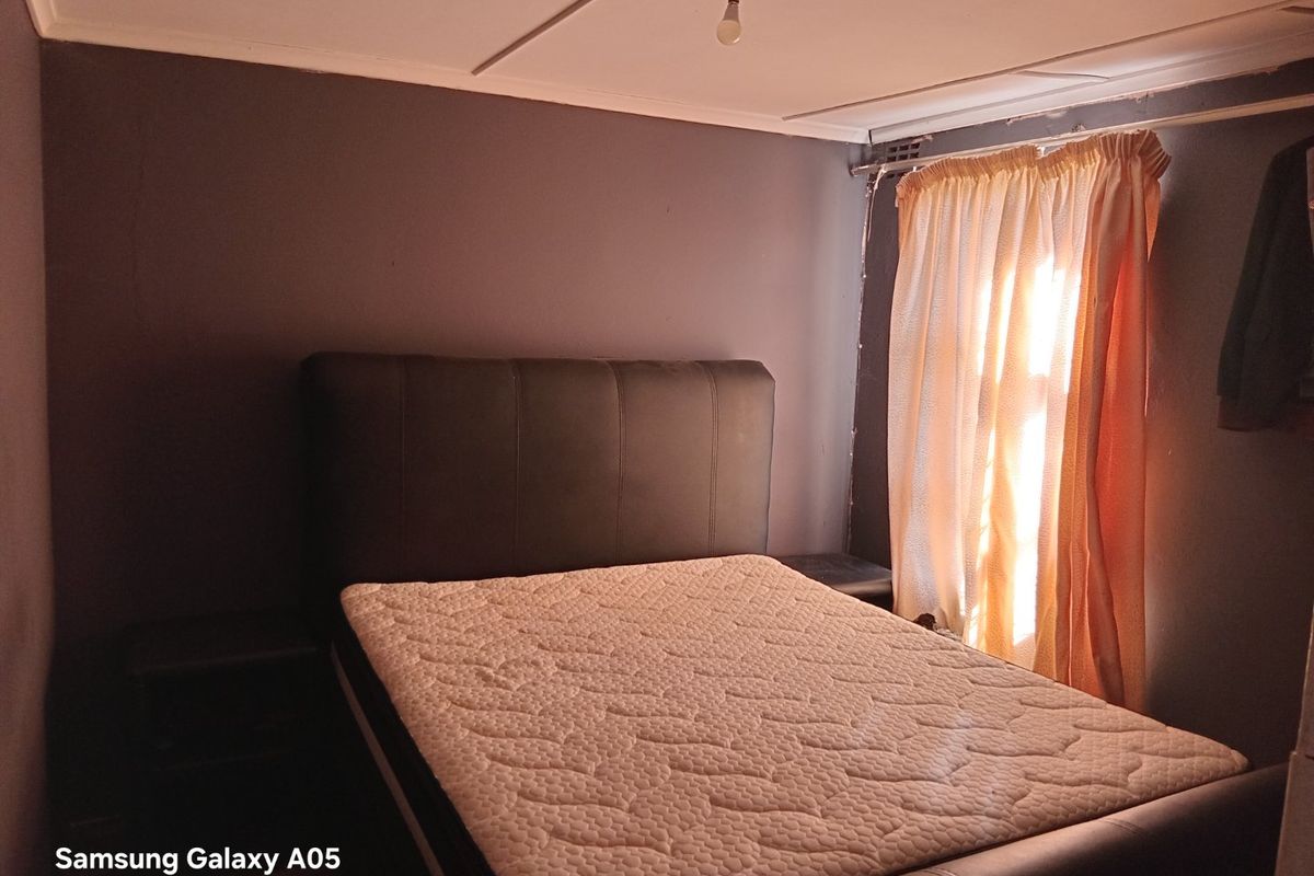 A bedroom featuring dark painted walls and a standard ceiling finish, requiring cosmetic updates to improve the overall aesthetic and finish quality.
