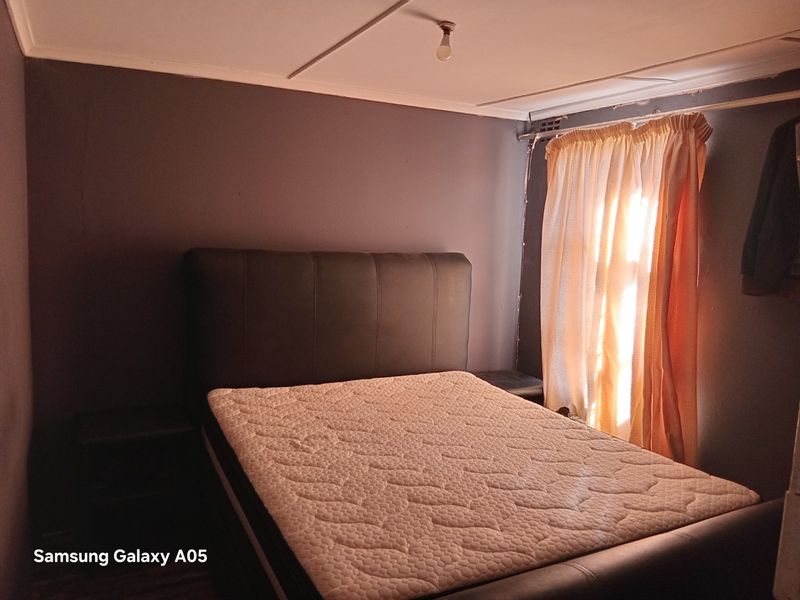 A bedroom featuring dark painted walls and a standard ceiling finish, requiring cosmetic updates to improve the overall aesthetic and finish quality.