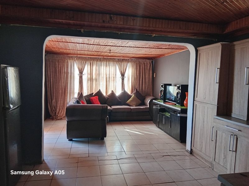 Open plan living area featuring timber tongue and groove ceilings, ceramic tiled flooring, and built-in cabinetry, with an arched transition between spaces.